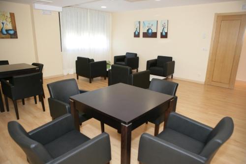 a waiting room with a table and chairs and a piano at HOTEL BRUMA II in La Gudiña