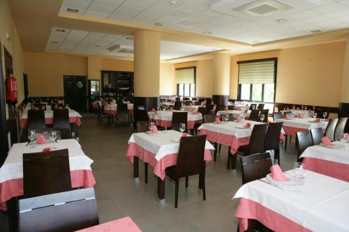 un restaurante con mesas y sillas rojas y blancas en HOTEL BRUMA II en La Gudiña
