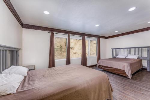 a bedroom with two beds and two windows at Mountain Trail Lodge and Vacation Rentals in Oakhurst