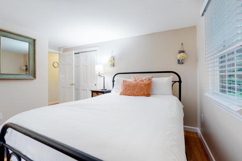 a white bed with orange pillows in a bedroom at Collingwood Cottage in Yarmouth Port