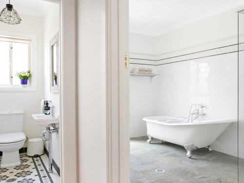 a white bathroom with a tub and a toilet at Ballogie Lodge in Bundanoon