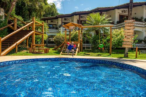 a woman sitting in a chair next to a swimming pool at Best Western Shalimar Praia Hotel in Porto Seguro