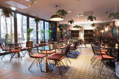 a dining room with tables and chairs and plants at Scandic Hamburger Börs in Turku