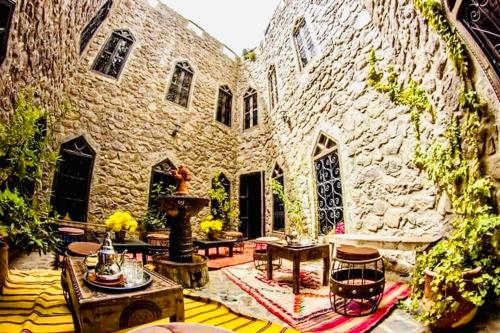 a large stone building with a courtyard with tables and chairs at Riad imlil in Imlil
