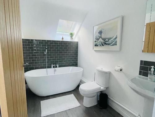 ein Badezimmer mit Badewanne, Toilette und Waschbecken in der Unterkunft Pipeline Cottage in Dolgarrog