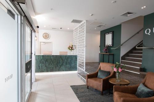 a lobby with two chairs and a staircase at Quest on London in Hamilton