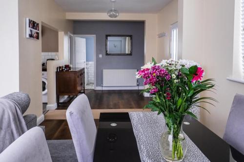 a vase of flowers on a table in a living room at Tallets Apartment with Balcony & Parking in Tewkesbury