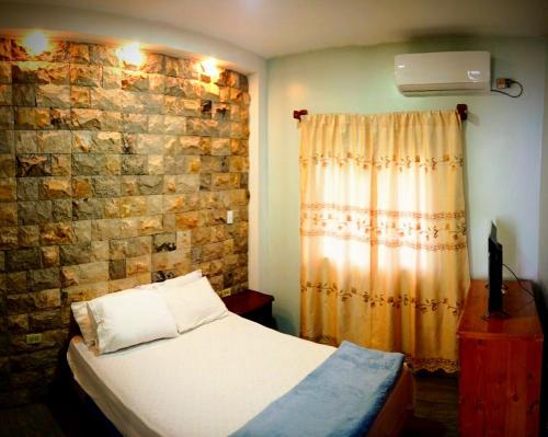 een slaapkamer met een bed en een bakstenen muur bij Casa Scalesia in Puerto Baquerizo Moreno
