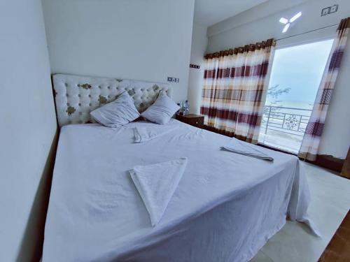a bedroom with a white bed with a window at Hotel Royal Beach & Restaurant in Jaliapāra