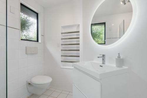 a white bathroom with a toilet and a sink at The Condo at Palm Beach by Waiheke Unlimited in Palm Beach