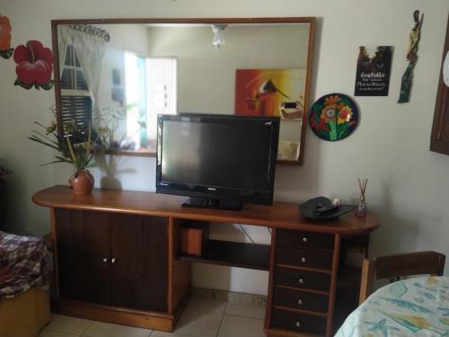 una TV su una scrivania in legno in camera di Casa temporada Peró Cabo Frio a Cabo Frio