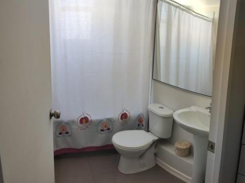 a white bathroom with a toilet and a sink at Departamento frente a aeropuerto in La Serena