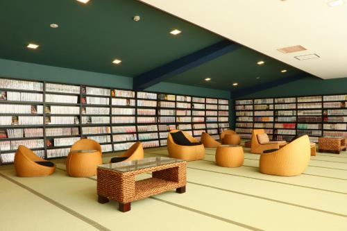 a library with chairs and a table and books at 将軍の湯 久能山本陣 Liberty Resort in Komagoe