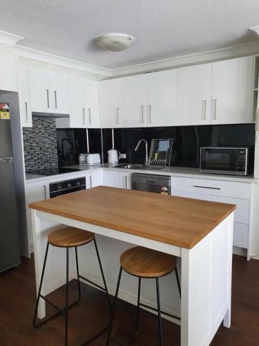 a kitchen with white cabinets and a wooden counter top at Bayview Bay Apartments and Marina in Gold Coast