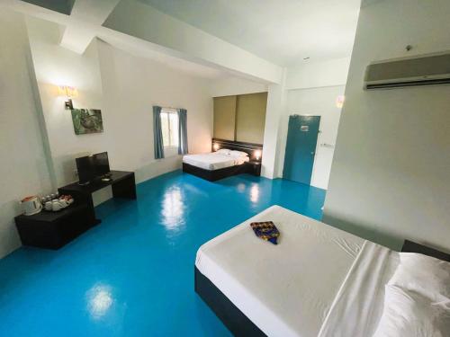 a room with two beds and a blue floor at Kuala Melaka Inn in Pantai Cenang