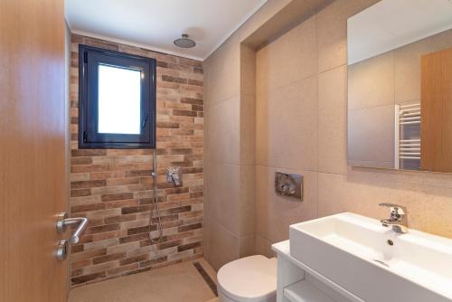 a bathroom with a sink and a toilet and a window at Domus Oliva Villas in Haraki