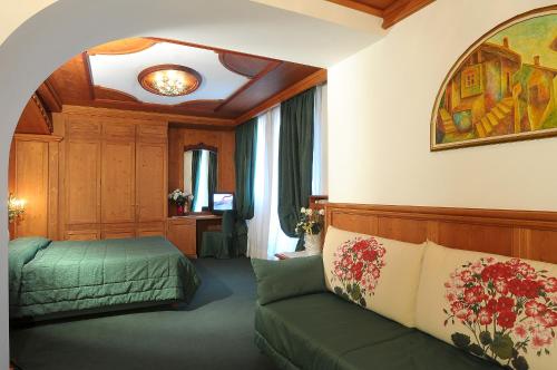 a bedroom with a green bed and a couch at Sporthotel Europa Sul Lago in Alleghe
