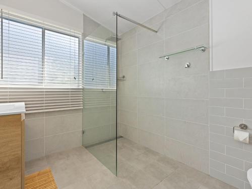 a bathroom with a glass shower and a sink at Husky Beach House by Experience Jervis Bay in Huskisson