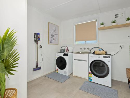 a laundry room with two washing machines and a sink at Husky Beach House by Experience Jervis Bay in Huskisson