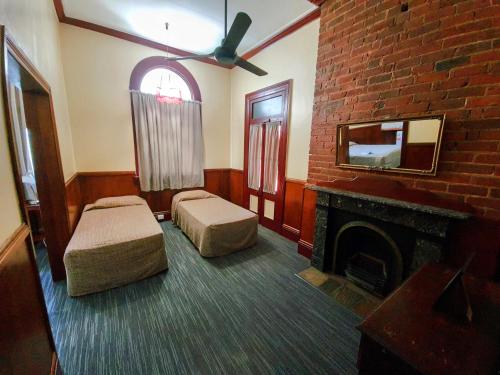 a living room with two beds and a fireplace at Criterion Hotel-Motel Rockhampton in Rockhampton
