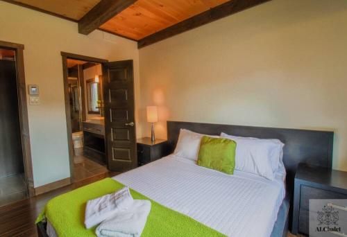 a bedroom with a bed with a green blanket at Chalet charmant - Détente familiale in Scott