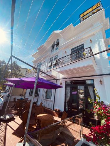 a patio with a purple umbrella in front of a building at Marguerite Villa in Da Lat