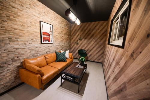a living room with a brown couch and a brick wall at Rusutsu Grand Cabin in Kimobetsu