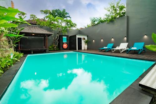 a swimming pool in the backyard of a house with blue chairs at Sunrise Aventus Hotel Nusa Dua in Nusa Dua