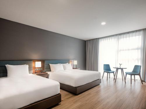 a hotel room with two beds and a table and chairs at Hotel Tops 10 in Gangneung
