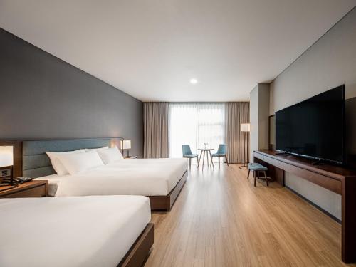 a hotel room with two beds and a flat screen tv at Hotel Tops 10 in Gangneung