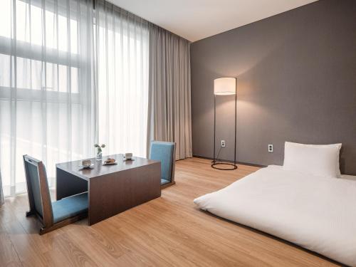 a bedroom with a bed and a desk and a bed and a window at Hotel Tops 10 in Gangneung