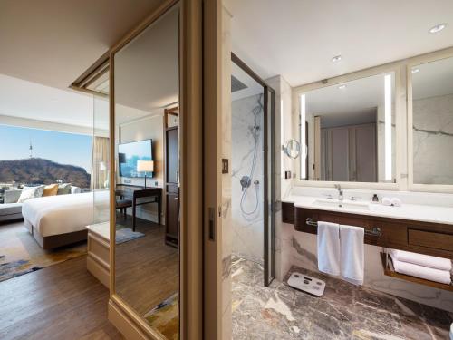 uma casa de banho com um chuveiro, um lavatório e uma cama em The Ambassador Seoul - A Pullman Hotel em Seul