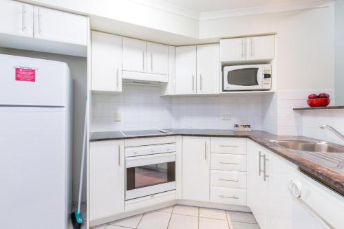 a kitchen with white cabinets and white appliances at Ramada Resort by Wyndham Shoal Bay in Shoal Bay