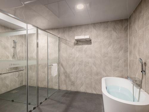 a bathroom with a shower and a bath tub at Hotel Tops 10 in Gangneung