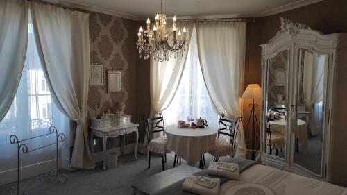 a bedroom with a bed and a table and a chandelier at La Clef Dort in Beauchamps