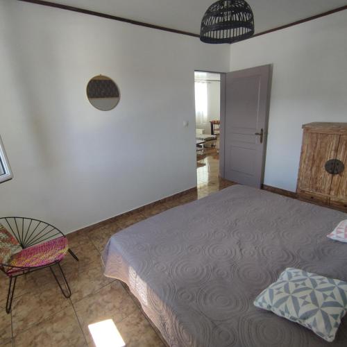 a bedroom with a bed and a chair at Spacieux appart T3 à st gilles les bains 80 m2, grande varangue, plage in Saint-Gilles-les-Bains