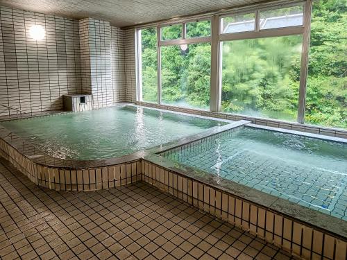 een groot zwembad met water in een kamer met een raam bij Hotel Nosegawa in Nosegawa