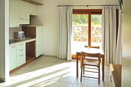 una cucina con tavolo, sedie e finestra di Terraced house in holiday residence Il Nido dei Gabbiani, Porto Pollo a Porto Pollo