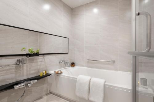 a white bathroom with a tub and a mirror at Hinode Hills Niseko Village in Niseko