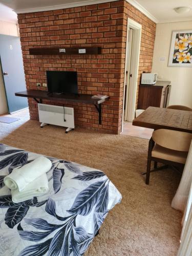 ein Wohnzimmer mit einem TV und einer Ziegelwand in der Unterkunft Toora Lodge Motel in Toora