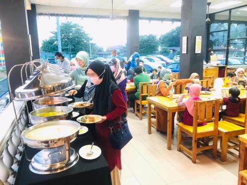 a group of people sitting in a restaurant eating food at DLAYARAN HOTEL & CAFE in Kuala Rompin