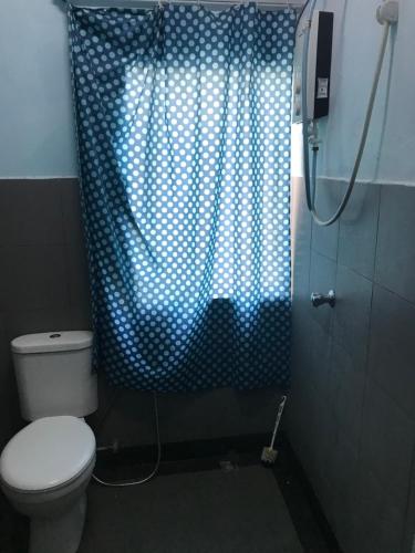 a bathroom with a toilet and a blue shower curtain at YB HOUSE in Kuantan