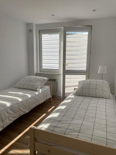 2 Betten in einem Zimmer mit 2 Fenstern in der Unterkunft Apartament -Dwudziestka in Sandomierz
