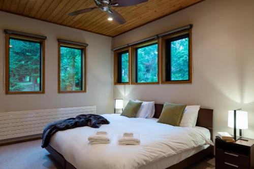 a bedroom with a large white bed with windows at Starchase by H2 Life in Niseko