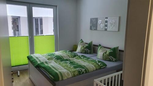 Un dormitorio con una cama con sábanas verdes y una ventana en Moderne, barrierefreie Ferienwohnung en Plauen
