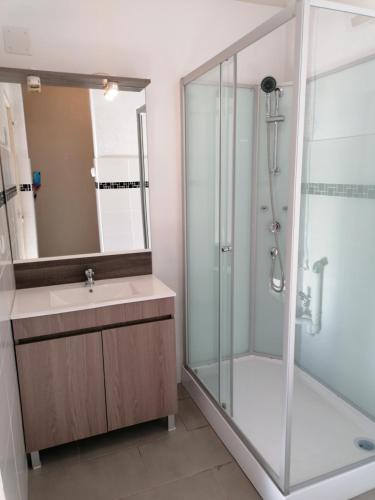 une salle de bain avec une douche en verre et un lavabo dans l'établissement Les Chalets la Plage - Etape Vacances, à Portiragnes