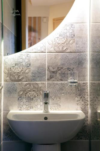 a white sink in a bathroom with a mirror at Designer apartments close to the center + free parking in Thessaloniki