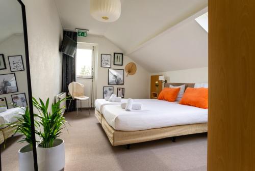 a bedroom with two beds with orange pillows at Hotel Restaurant de Loenermark in Loenen