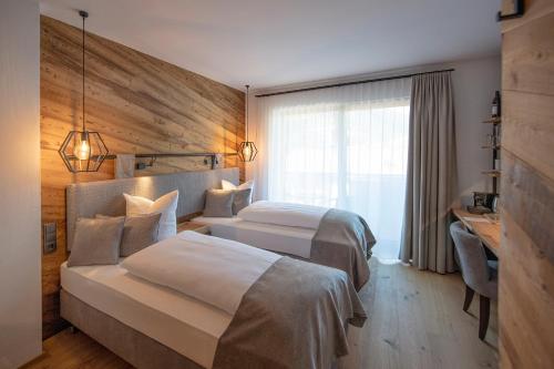 a hotel room with two beds and a desk at Hotel Edelweiss in Saalbach Hinterglemm