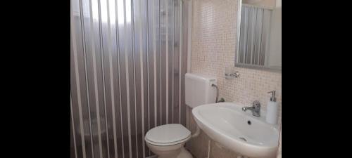 a bathroom with a white toilet and a sink at Giardino dei Baroni house in Marina di Mancaversa